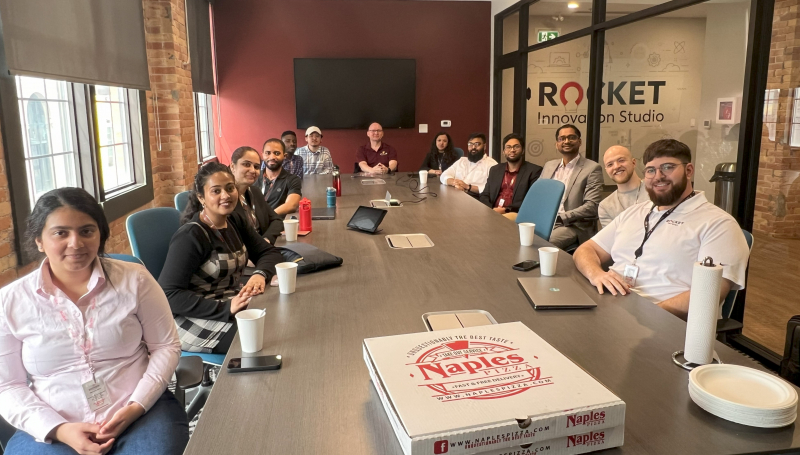 People sitting at conference room table with pizza boxes